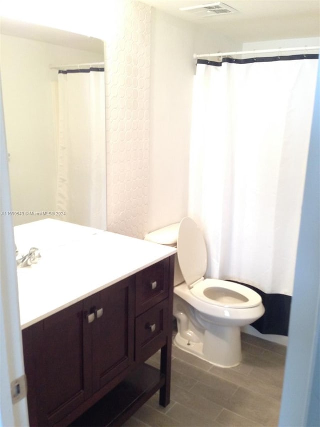 bathroom with hardwood / wood-style floors, vanity, and toilet