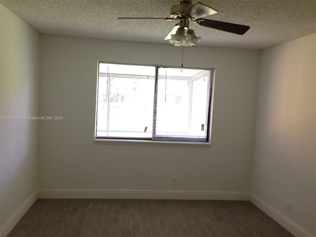 unfurnished room featuring dark wood-type flooring, ceiling fan, and a textured ceiling