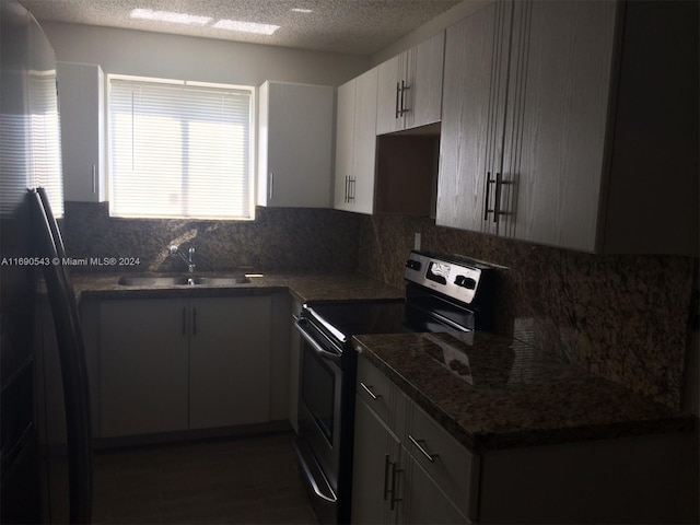 kitchen with dark stone counters, a textured ceiling, sink, backsplash, and stainless steel electric stove