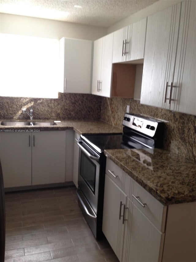 kitchen with stainless steel range with electric stovetop, dark stone counters, white cabinetry, a textured ceiling, and dark wood-type flooring