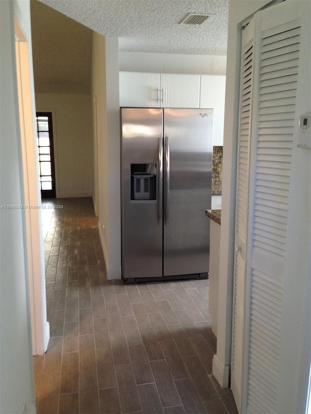 kitchen featuring a textured ceiling, stone countertops, dark hardwood / wood-style flooring, stainless steel refrigerator with ice dispenser, and white cabinets