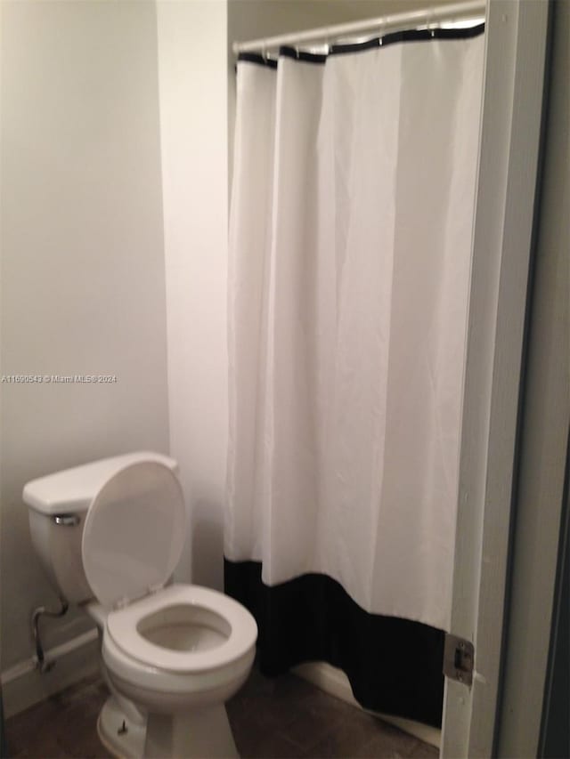 bathroom with toilet and a shower with curtain