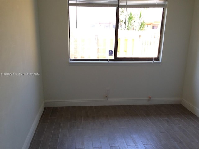 spare room with dark hardwood / wood-style floors and a healthy amount of sunlight