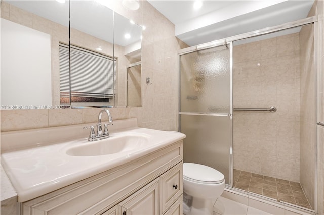 bathroom featuring tile walls, vanity, toilet, and a shower with door