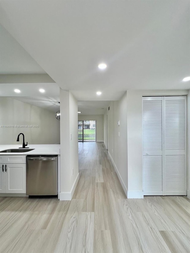 kitchen featuring white cabinetry, dishwasher, sink, and light hardwood / wood-style flooring