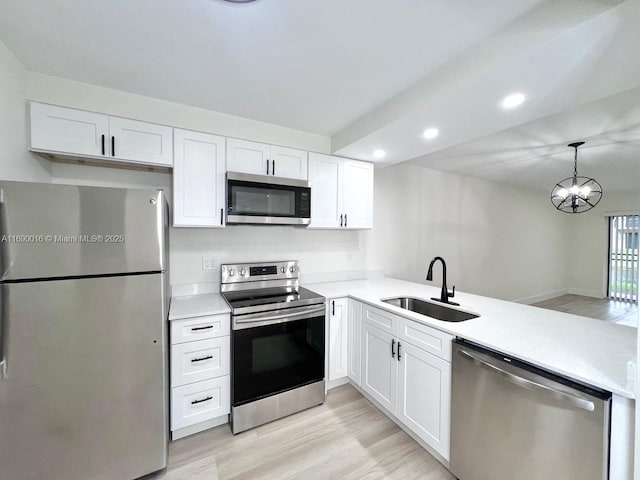 kitchen featuring appliances with stainless steel finishes, white cabinetry, hanging light fixtures, a chandelier, and sink