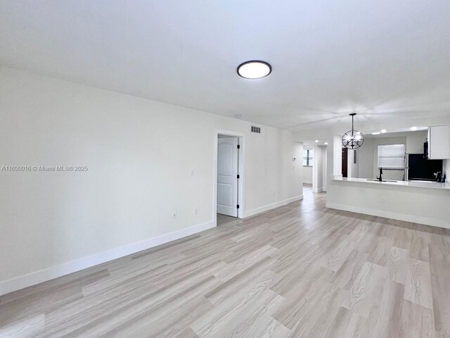 spare room with a notable chandelier and light hardwood / wood-style floors