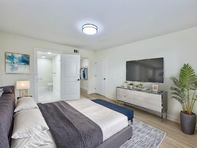 bedroom featuring a closet, light wood-type flooring, and connected bathroom