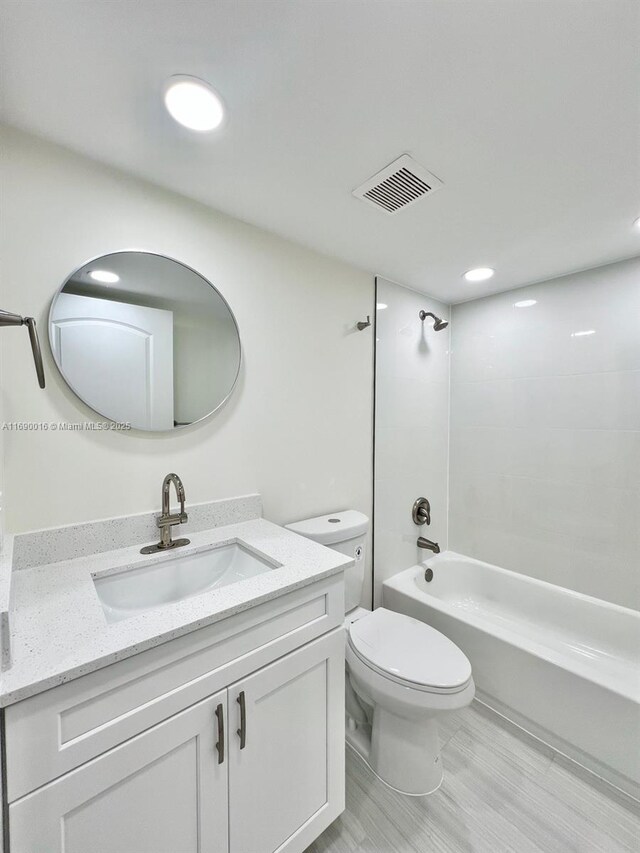 full bathroom with hardwood / wood-style floors, toilet, bathtub / shower combination, and vanity