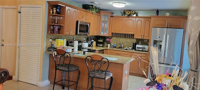 kitchen featuring light tile patterned flooring, sink, stainless steel appliances, light stone countertops, and decorative backsplash