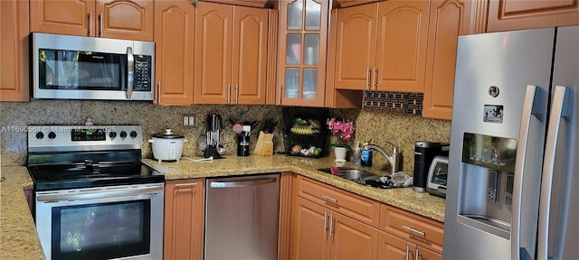 kitchen with light stone countertops, backsplash, stainless steel appliances, and sink