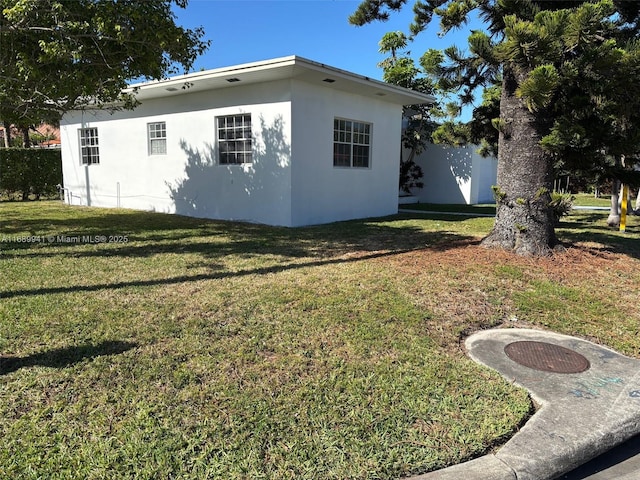 view of front of property with stucco siding, an attached garage, driveway, and a front lawn