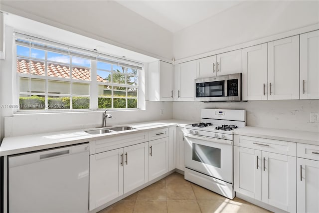 kitchen with white cabinets, white appliances, light tile patterned flooring, and sink