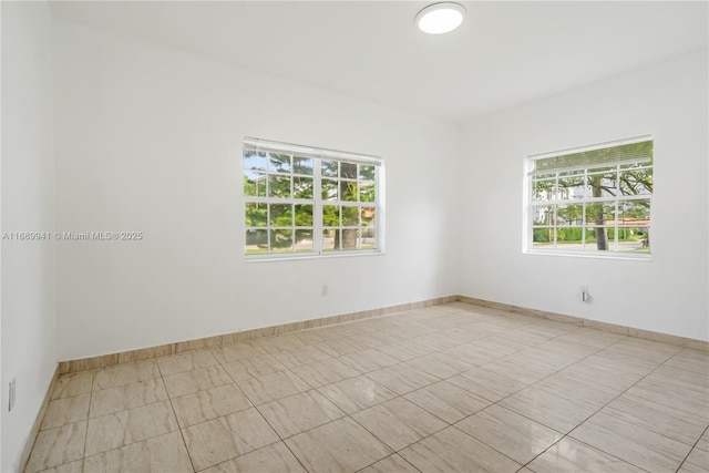 empty room featuring plenty of natural light and baseboards
