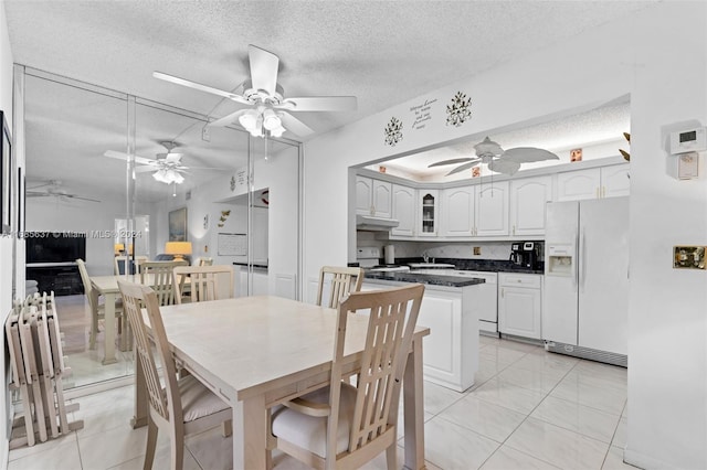 tiled dining area with sink, a textured ceiling, and vaulted ceiling