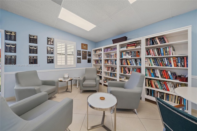 living area featuring a drop ceiling and light tile patterned flooring