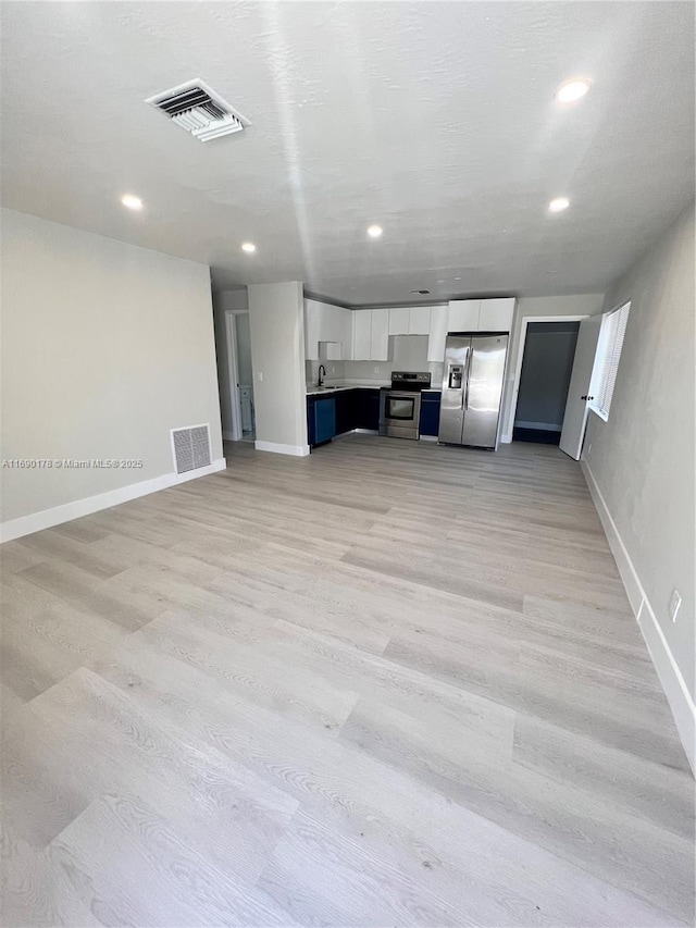 unfurnished living room with sink and light hardwood / wood-style floors