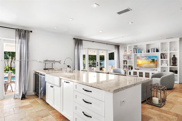 kitchen with sink, light stone countertops, white cabinets, dishwasher, and french doors