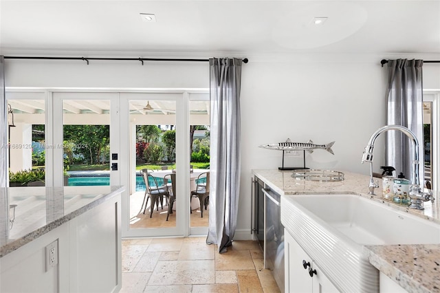 kitchen with dishwasher, white cabinetry, sink, and light stone counters