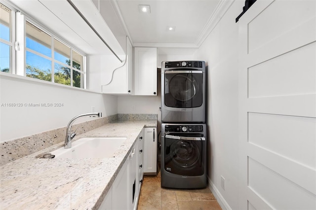 laundry area with crown molding, cabinets, stacked washer / drying machine, and sink