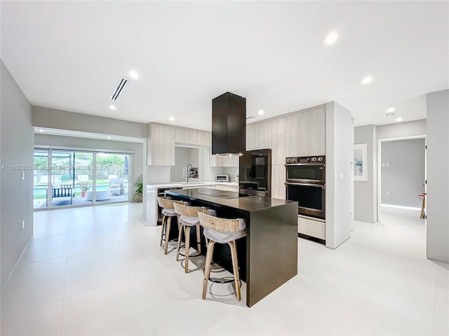 kitchen featuring a breakfast bar, a center island, black appliances, sink, and light tile patterned floors