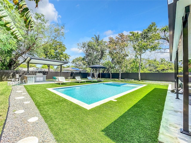 view of swimming pool with a lawn and exterior bar