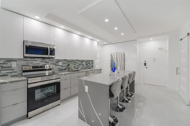 kitchen with white cabinetry, a barn door, a center island, and stainless steel appliances