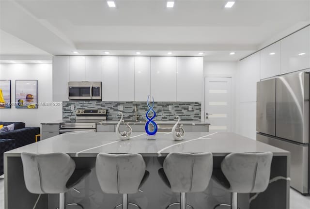 kitchen featuring tasteful backsplash, appliances with stainless steel finishes, a large island, and white cabinets