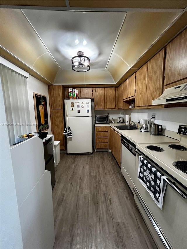 kitchen with white appliances, sink, vaulted ceiling, a tray ceiling, and dark hardwood / wood-style flooring