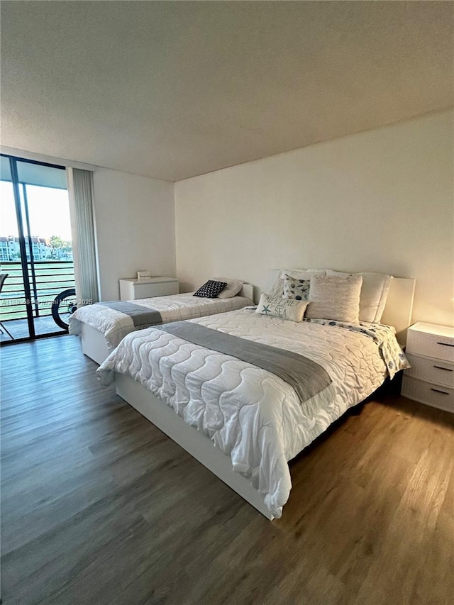 bedroom with access to exterior, dark hardwood / wood-style flooring, and floor to ceiling windows