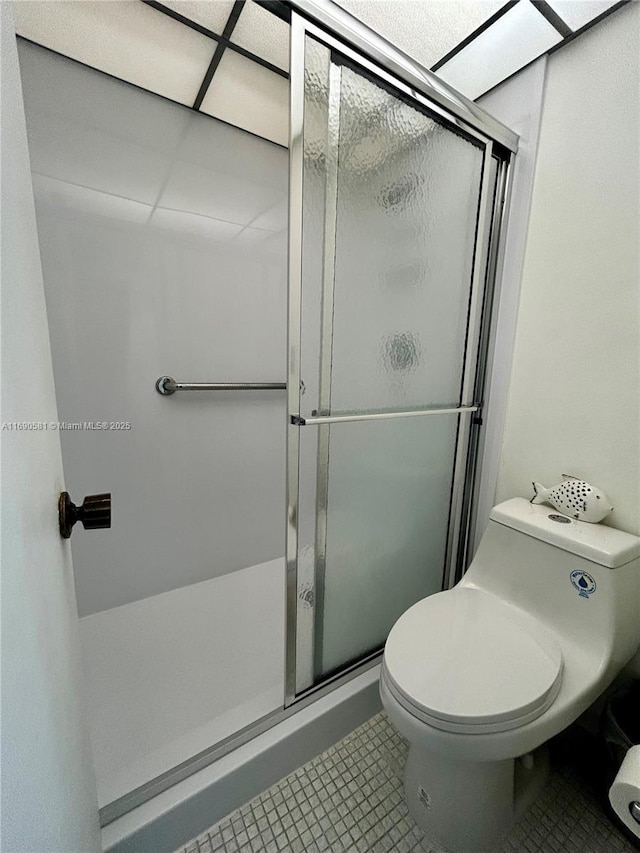 bathroom featuring tile patterned floors, toilet, and a shower with door