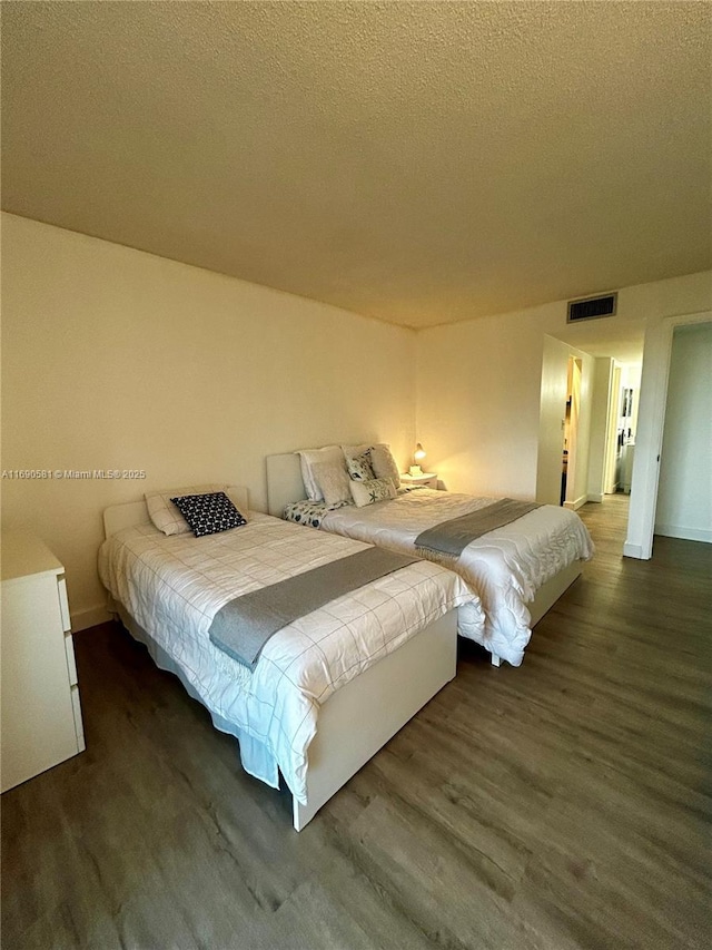 bedroom with dark wood-type flooring and a textured ceiling