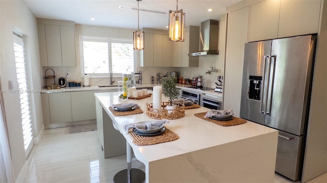 kitchen with sink, appliances with stainless steel finishes, a kitchen breakfast bar, wall chimney exhaust hood, and a kitchen island