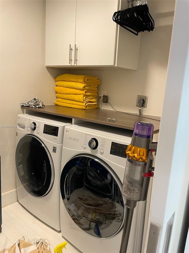 clothes washing area featuring washing machine and dryer, cabinets, and light tile patterned floors