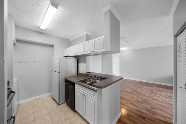 kitchen with light wood-type flooring, a textured ceiling, sink, white cabinets, and dishwasher