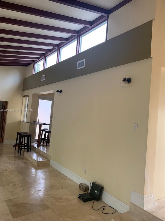 spare room with a towering ceiling and beam ceiling