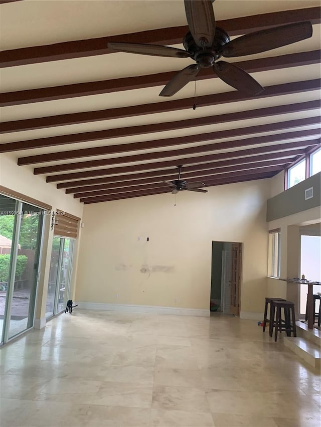 spare room featuring beamed ceiling, a healthy amount of sunlight, and ceiling fan