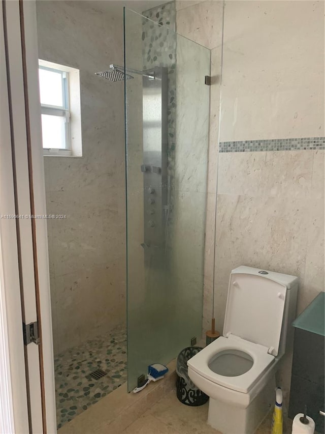 bathroom with tile patterned flooring, tiled shower, and toilet