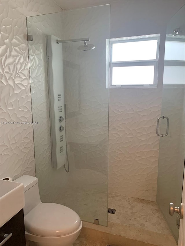 bathroom with toilet, vanity, and a shower with door