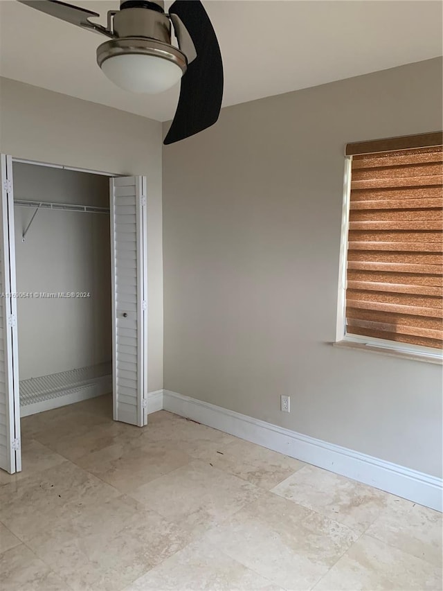 unfurnished bedroom with ceiling fan and a closet