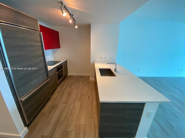 kitchen featuring light wood-type flooring, track lighting, sink, oven, and black electric cooktop