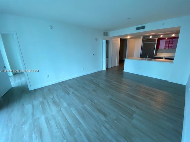 unfurnished living room with hardwood / wood-style floors, sink, and track lighting