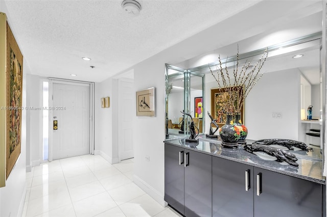 hallway with a textured ceiling and light tile patterned floors