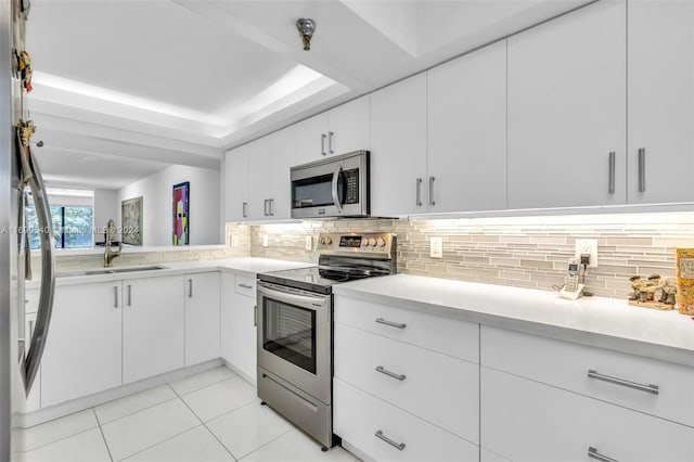 kitchen featuring light tile patterned flooring, white cabinetry, sink, appliances with stainless steel finishes, and backsplash