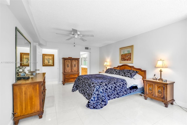 tiled bedroom with a textured ceiling, ensuite bathroom, and ceiling fan