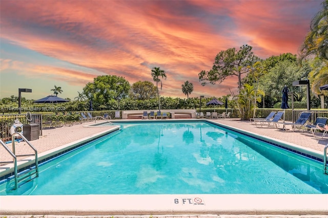 pool at dusk featuring a patio area