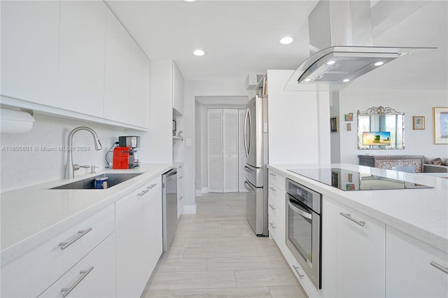 kitchen featuring island range hood, white cabinetry, appliances with stainless steel finishes, and sink