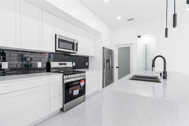 kitchen with sink, backsplash, light stone countertops, white cabinetry, and appliances with stainless steel finishes