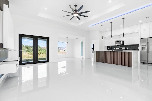 kitchen with a kitchen island, appliances with stainless steel finishes, decorative light fixtures, a raised ceiling, and ceiling fan