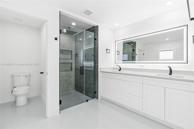 bathroom featuring a shower with shower door, vanity, and toilet